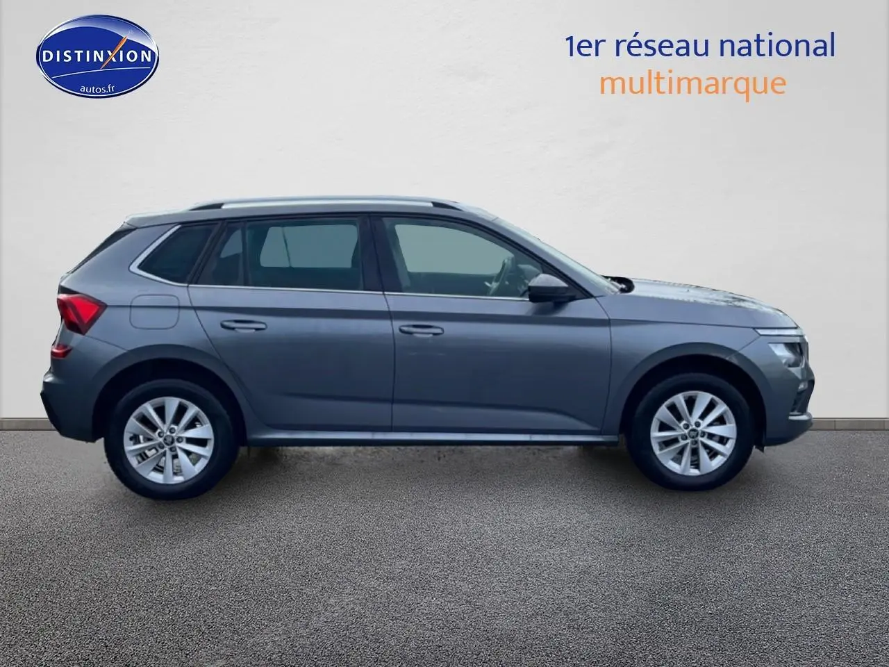 Vue latérale droite d'un Skoda Kamiq gris 2025 avec jantes alu et barres de toit visibles.