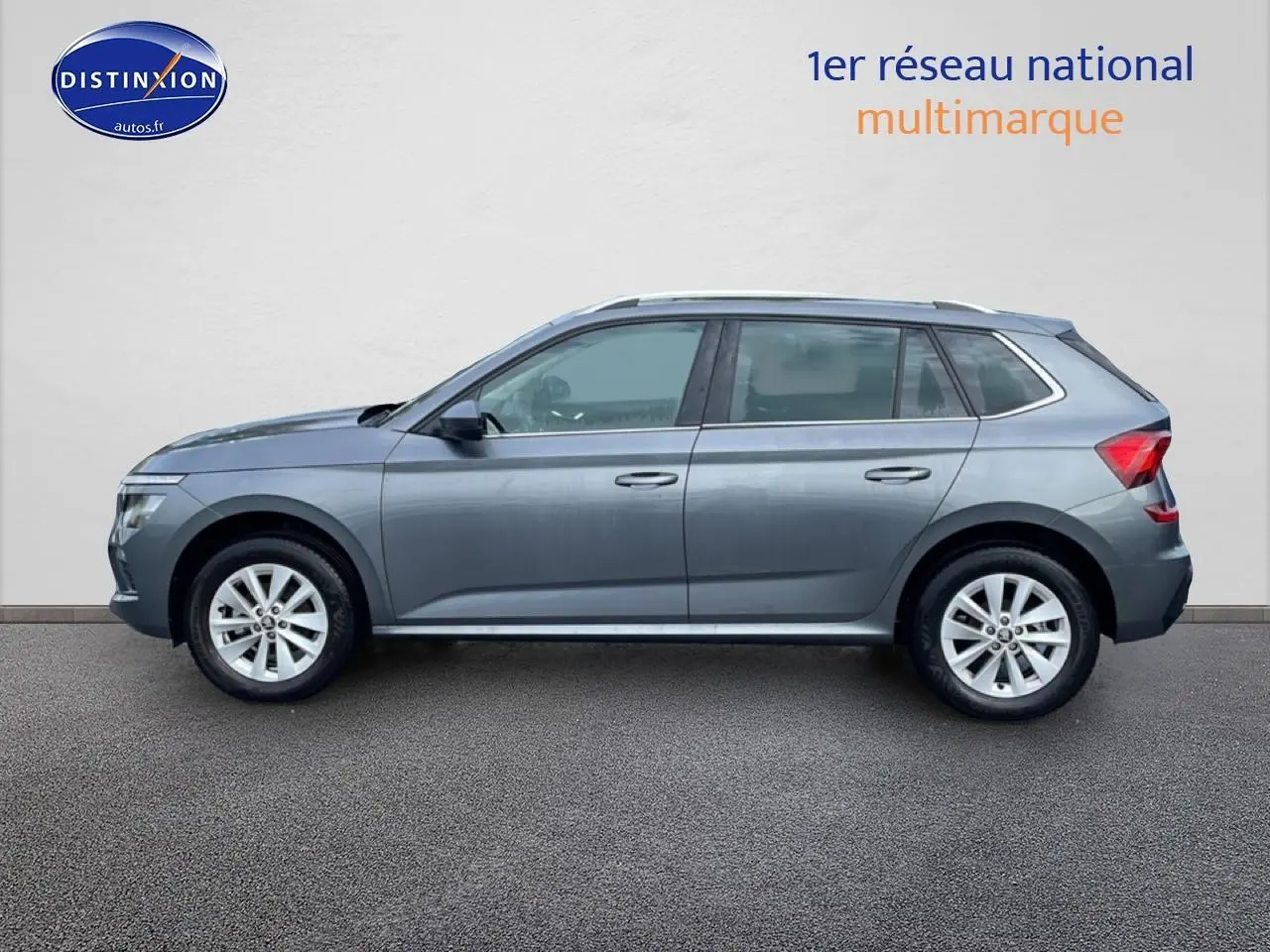 Vue latérale droite d'un Skoda Kamiq gris 2025 avec jantes alu et barres de toit visibles.