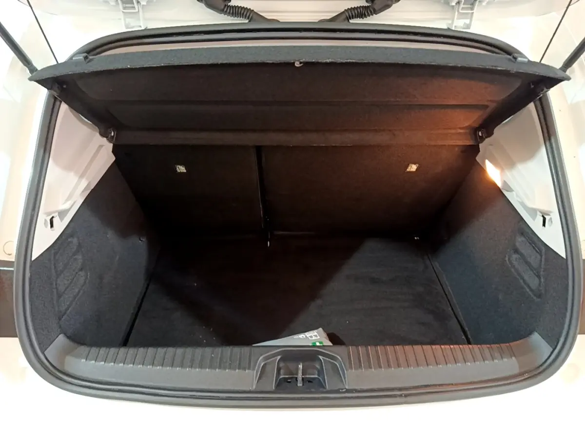 Coffre ouvert vu de face d'une Renault Clio Business blanche, montrant l'espace de chargement vide et l'éclairage intérieur.