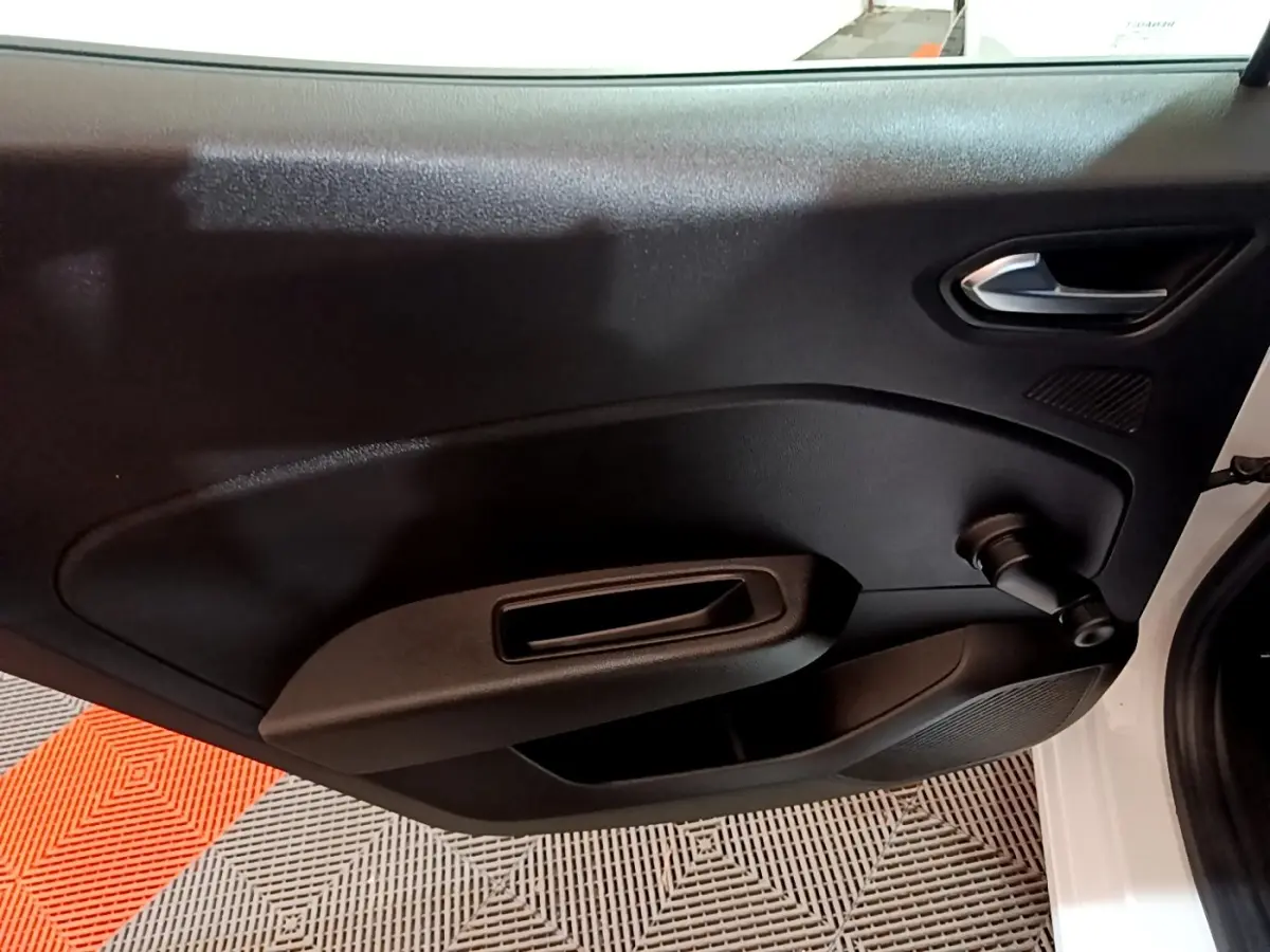 Vue intérieure côté gauche de la porte avant d'une Renault Clio Business blanche avec manivelle de vitre manuelle.