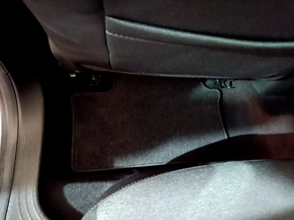 Vue rapprochée du tapis de sol noir situé au sol côté arrière d’une Renault Clio Business blanche de 2021.