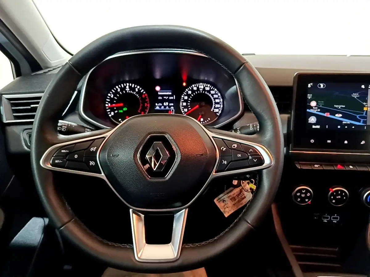 Vue intérieure centrée sur le volant cuir noir de la Renault Clio Business avec tableau de bord et écran tactile visible à droite.