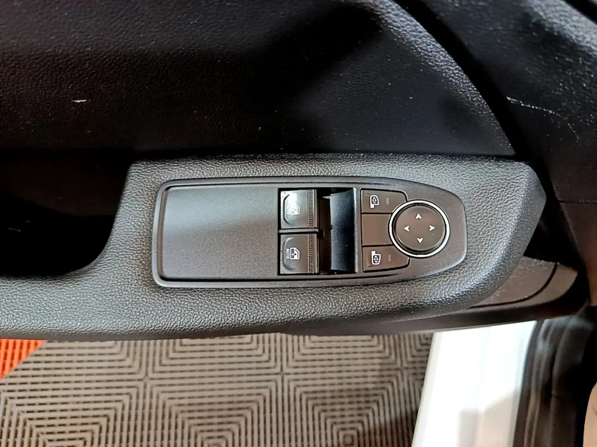 Gros plan sur les commandes de lève-vitres et réglage des rétroviseurs côté conducteur d’une Renault Clio blanche 2021.