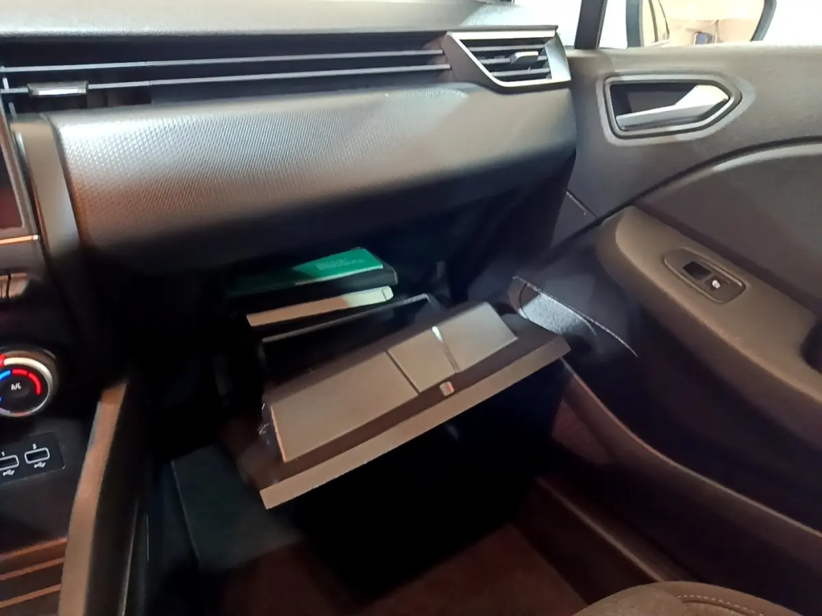 Intérieur de la Renault Clio Business blanc, vue côté passager sur la boîte à gants ouverte et tableau de bord noir.