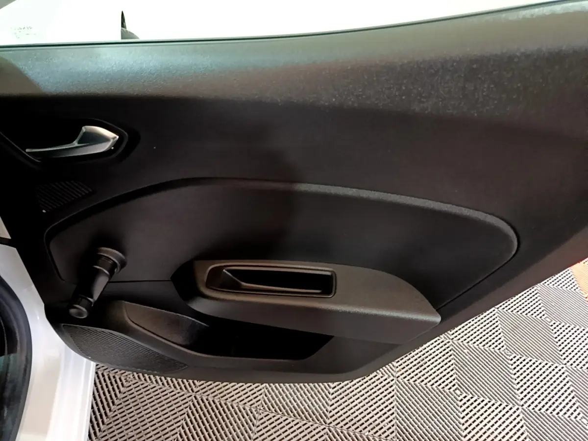 Vue rapprochée de la porte intérieure côté gauche d’une Renault Clio Business blanche, avec manivelle de vitre.