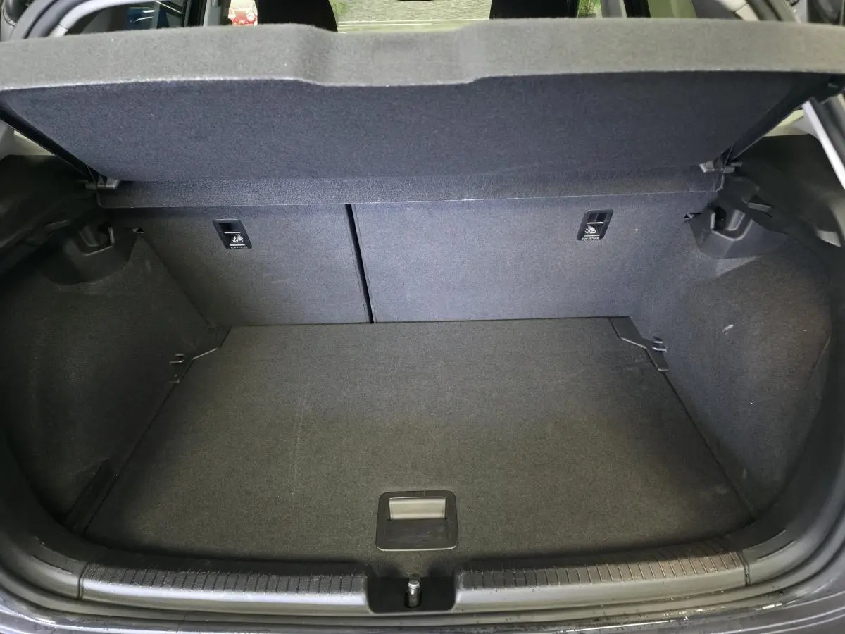 Coffre ouvert vu de l'arrière d'une Volkswagen Polo gris, montrant un espace de chargement propre et vide.