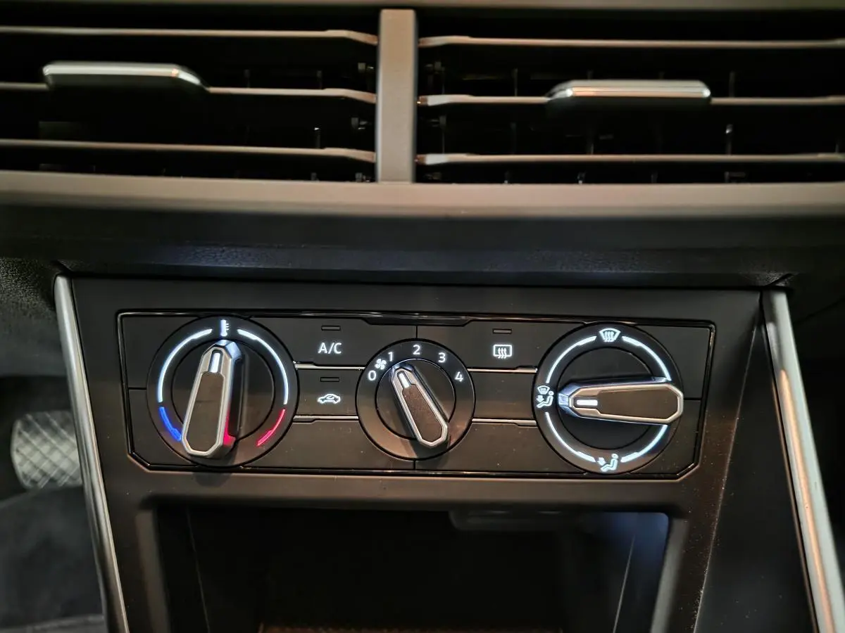 Gros plan sur la commande de climatisation manuelle noire du tableau de bord de la Volkswagen Polo gris 2025.