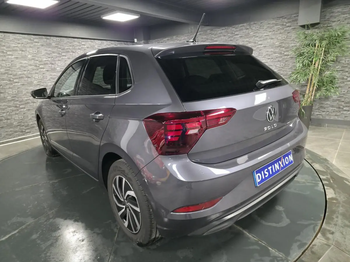 Vue 3/4 arrière gauche d'une Volkswagen Polo gris métallisé avec jantes alliage et vitres arrière surteintées.
