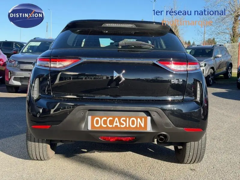 Vue arrière d'une DS3 Crossback noire 2020 avec feux LED et becquet, en extérieur sur parking.