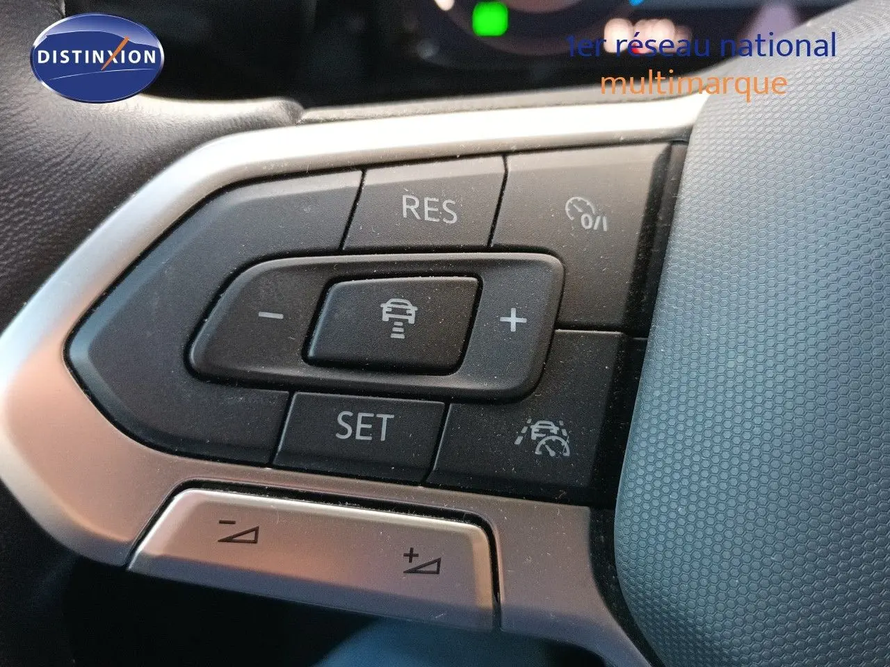 Gros plan sur les commandes au volant côté gauche de la Volkswagen Golf gris Urano 2024, boutons de régulateur de vitesse et assistance.
