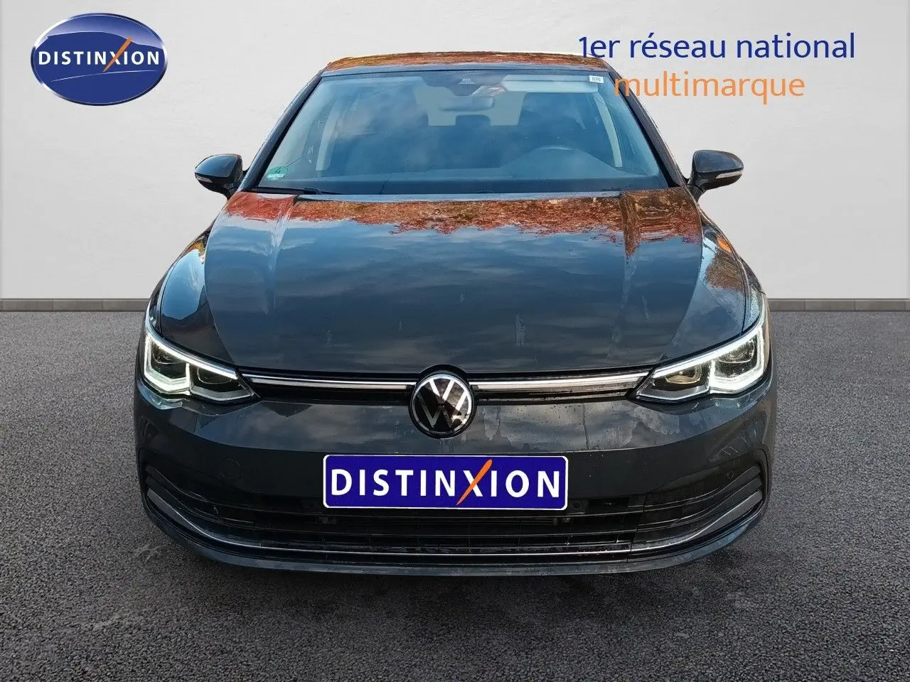 Vue frontale d'une Volkswagen Golf 1.5 TSI 130CH Style gris Urano avec phares LED allumés sur fond neutre.