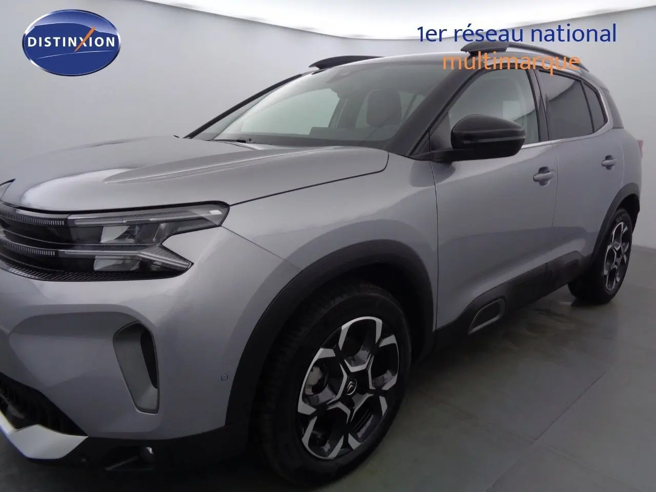 Vue 3/4 avant droit d'un Citroën C5 Aircross gris Artense métallisé avec jantes bi-ton et toit noir contrasté.