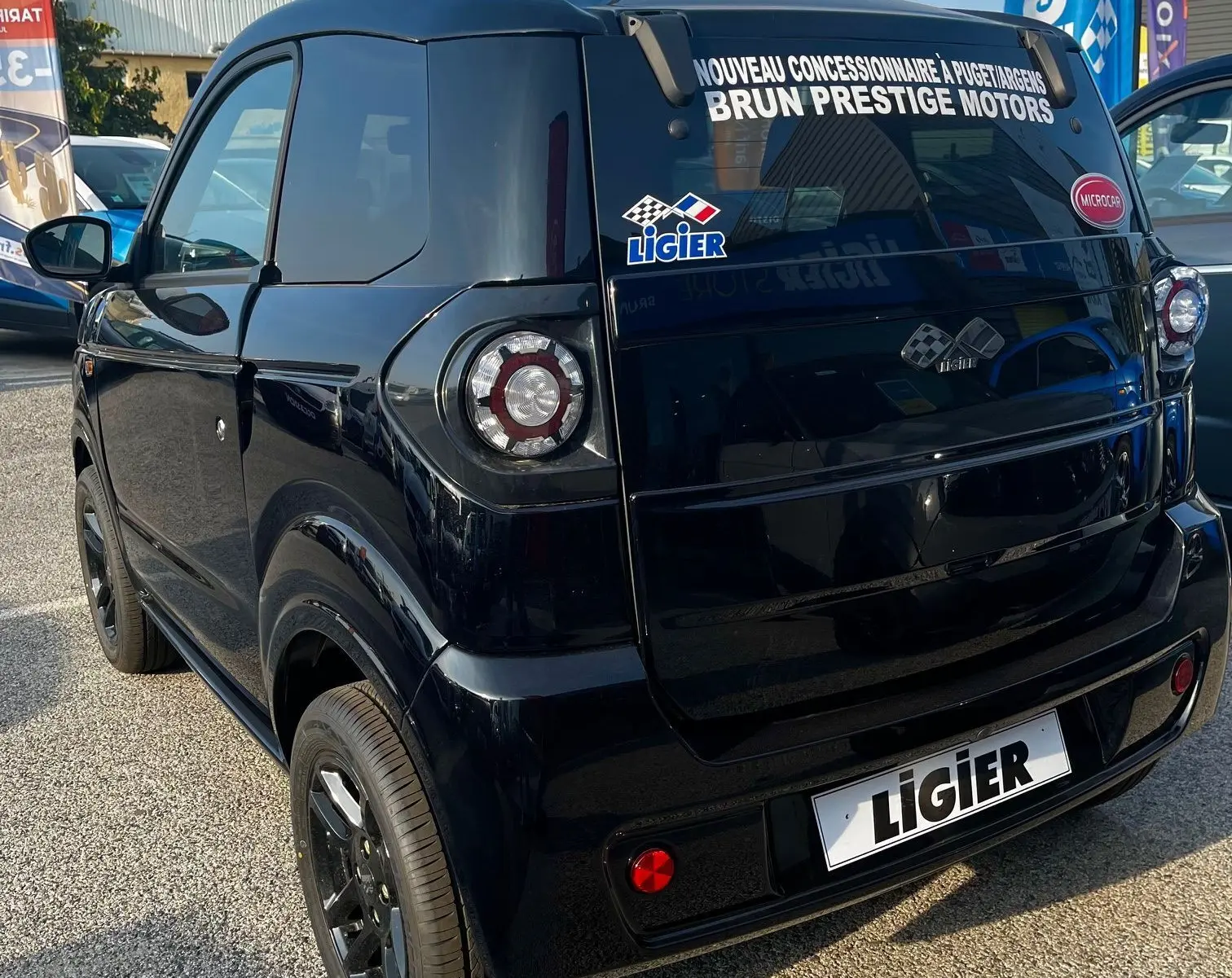 Vue 3/4 arrière droite d'une Ligier Myli I.DEL 8KWH noire intense avec vitres teintées et stickers concessionnaire.