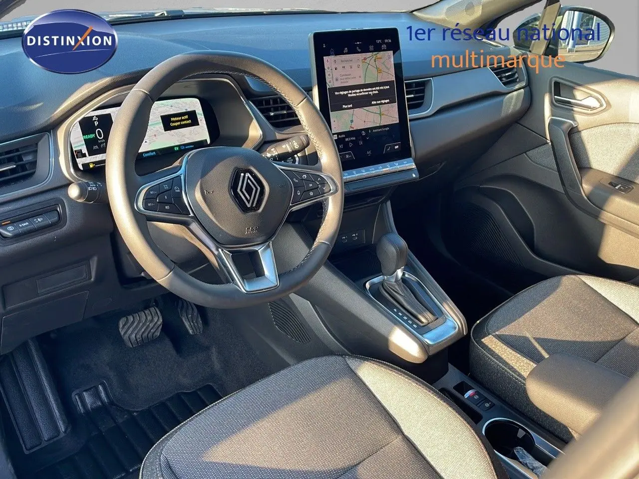 Intérieur Renault Captur E-Tech 2025 vu côté conducteur, volant multifonction et écran tactile central lumineux.