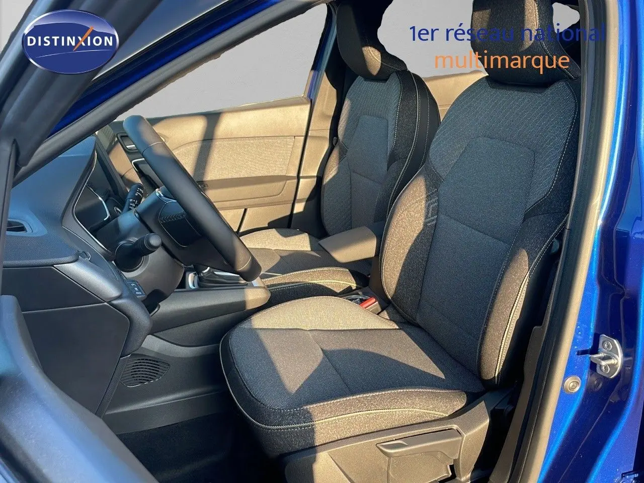 Vue intérieure côté conducteur du Renault Captur E-Tech Hybrid 2025 avec sièges tissu gris et bleu iron metal visible.