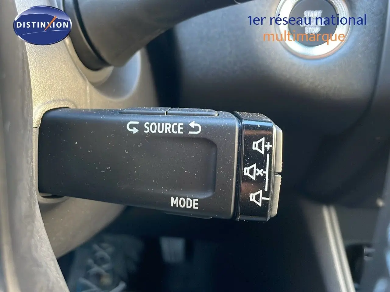 Gros plan sur la commande au volant du Renault Captur E-Tech hybride 2025, avec bouton source et mode visible.