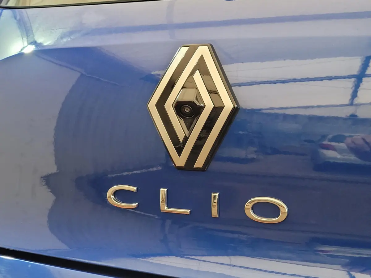 Gros plan sur le logo Renault et l’inscription Clio sur la malle arrière d’une Renault Clio bleu brillant.