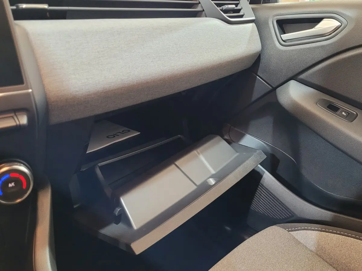 Intérieur de la Renault Clio Evolution Blue dCi 100 2025, vue côté passager avec boîte à gants ouverte et tableau de bord gris.