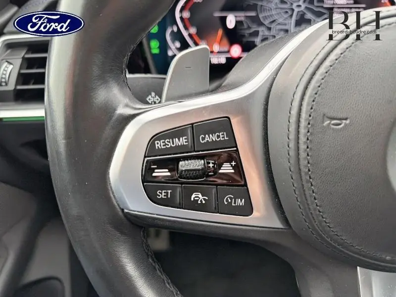 Gros plan sur le volant cuir noir de la BMW Série 4 Gran Coupe, boutons de régulateur de vitesse visibles côté gauche.