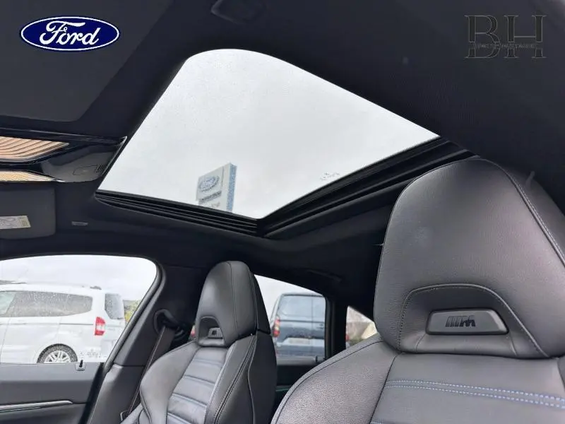 Vue intérieure sur les sièges avant cuir noir avec logo M et toit ouvrant en verre d'une BMW Série 4 Gran Coupé F36.