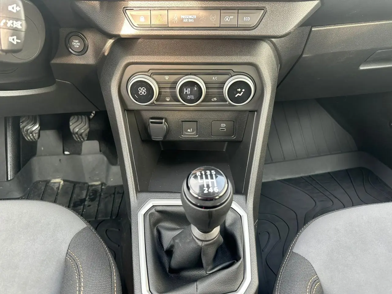 Vue rapprochée de la console centrale de la Dacia Sandero III Stepway, avec levier de vitesse manuel et commandes de climatisation.