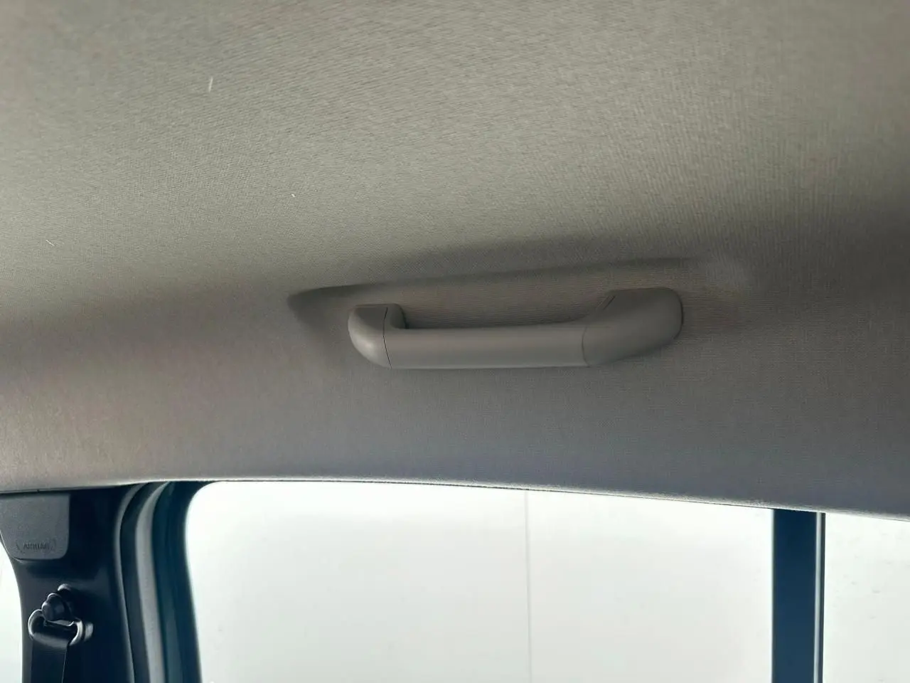 Poignée de maintien intérieure côté passager arrière d'une Dacia Sandero III Stepway 2025, tissu gris clair.