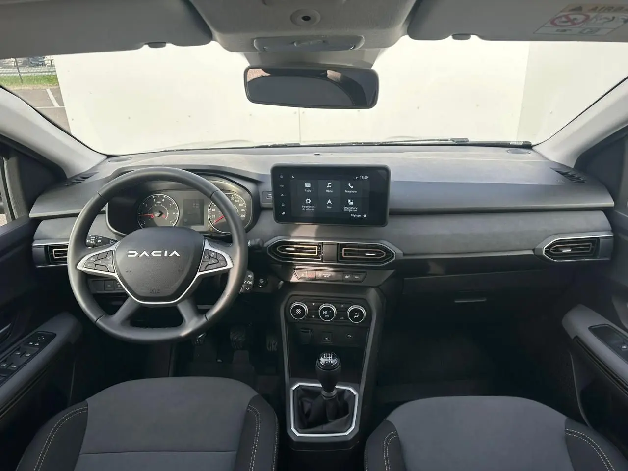 Vue intérieure avant du tableau de bord et volant noir de la Dacia Sandero III Stepway avec écran tactile central.