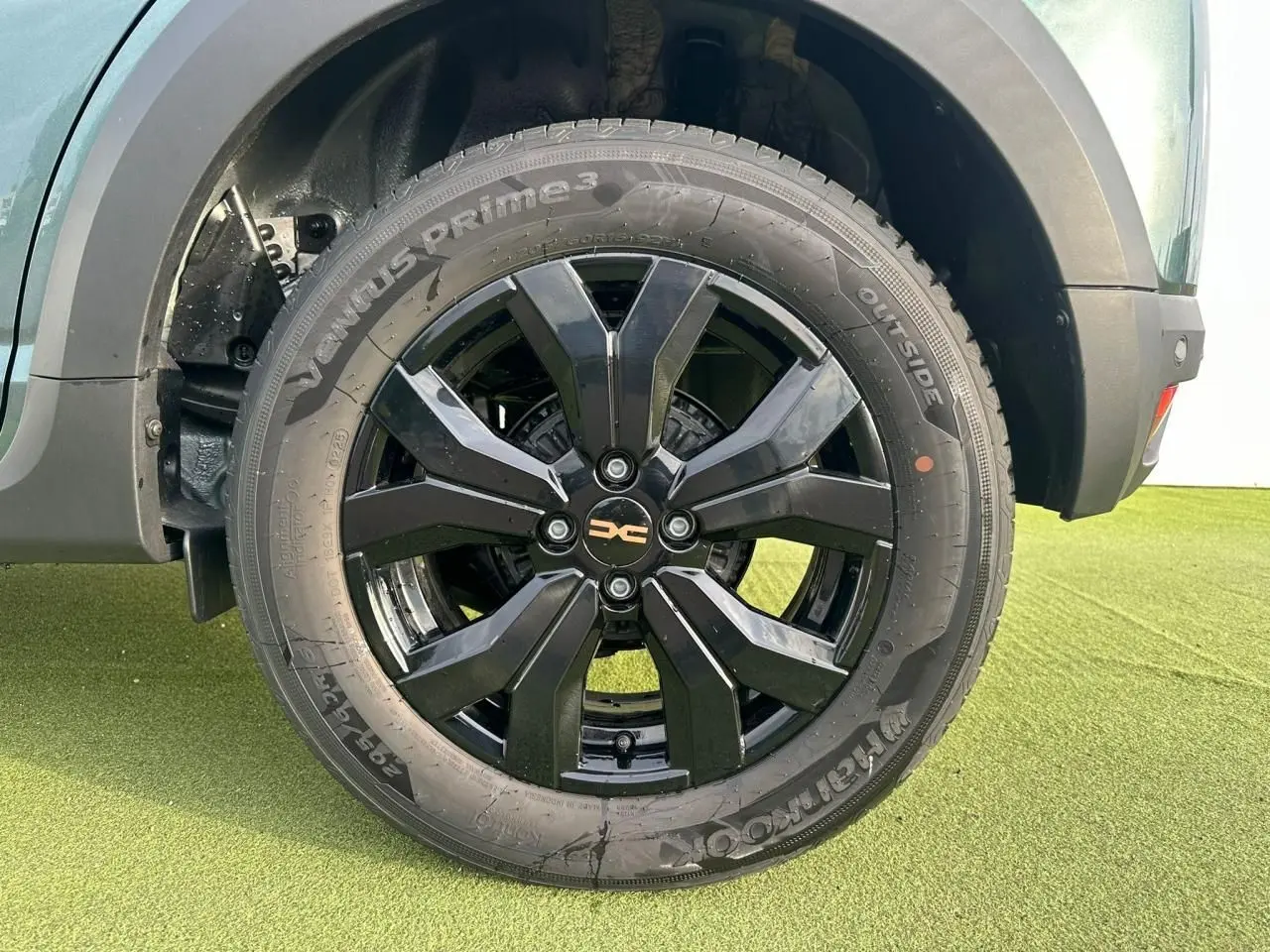 Gros plan sur la roue avant droite de la Dacia Sandero III Stepway vert cèdre avec jante aluminium noire brillante.