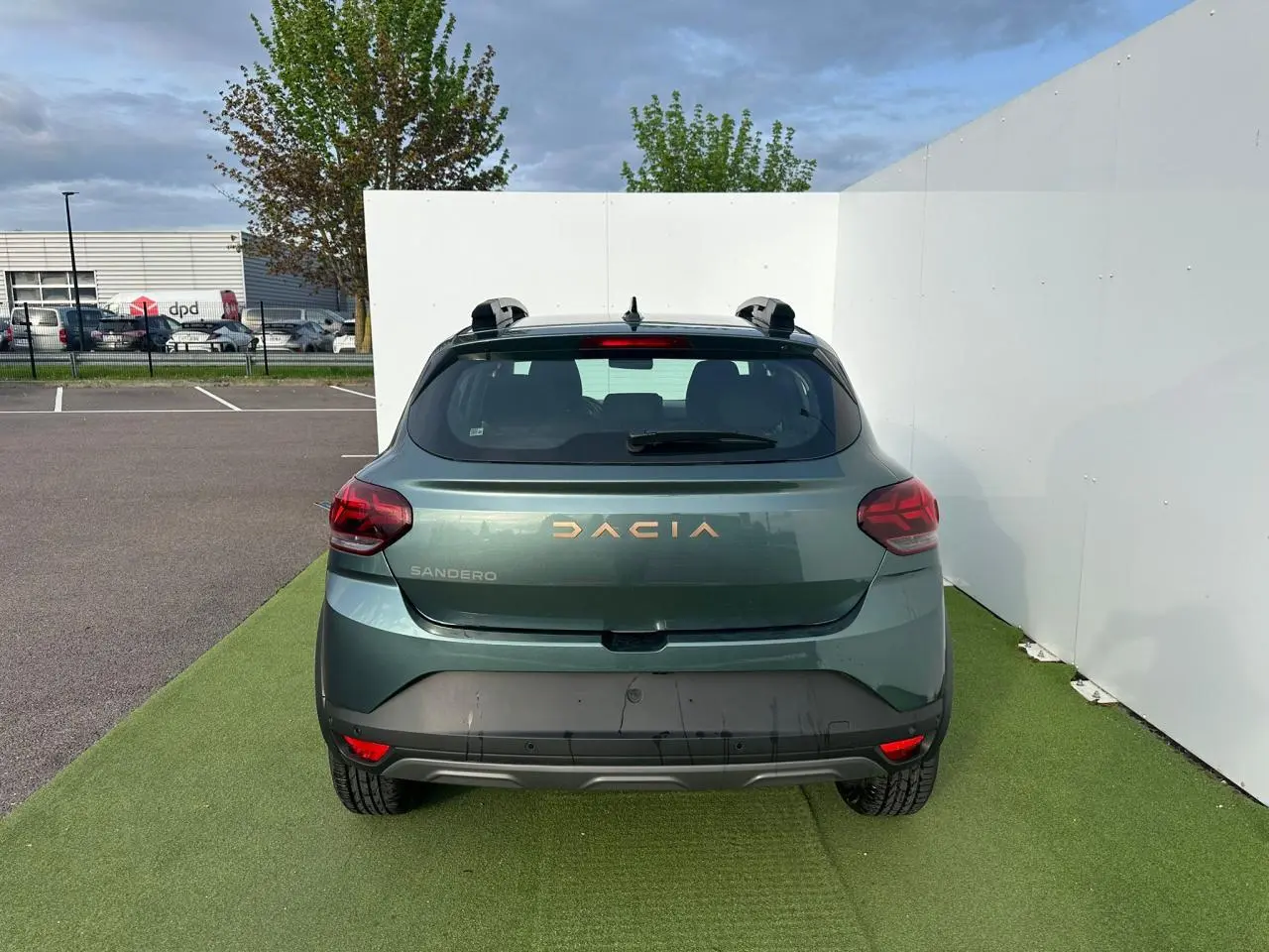 Vue arrière d'une Dacia Sandero III Stepway vert cèdre avec logo et feux arrière LED visibles.