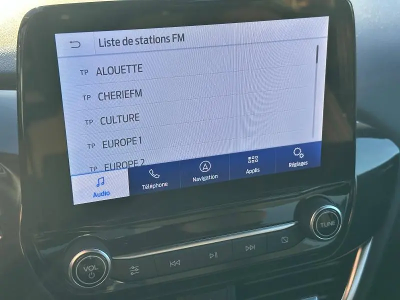 Écran tactile central du Ford Puma 2024 affichant la liste des stations FM, avec commandes audio en dessous.