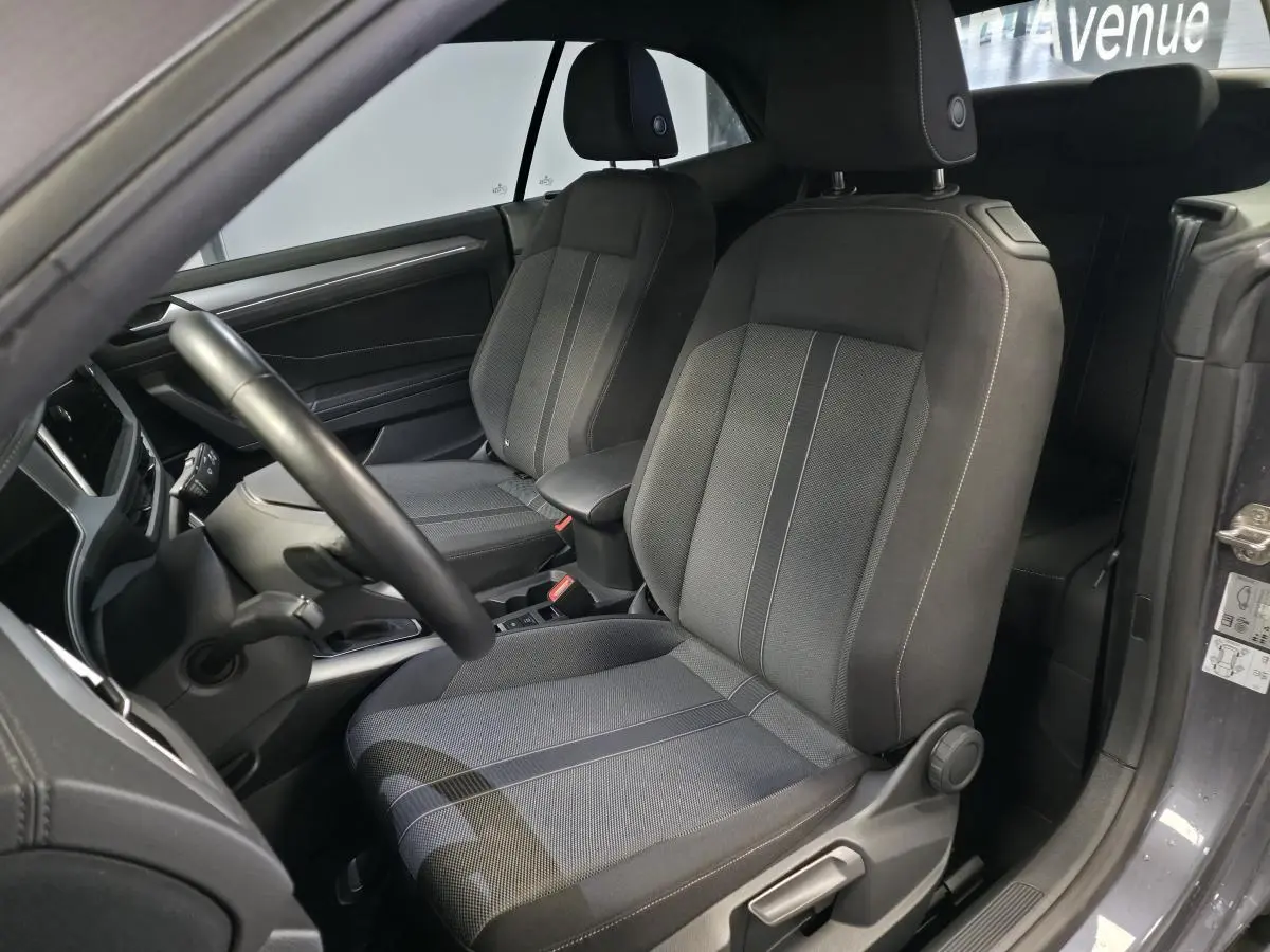 Vue intérieure côté gauche sur les sièges avant en tissu noir du Volkswagen T-Roc Cabriolet gris 2024.