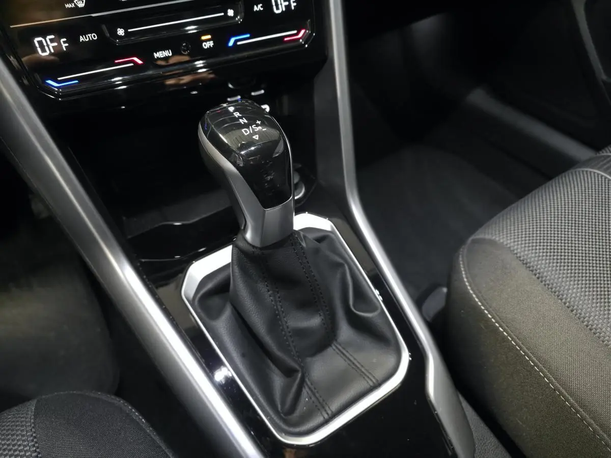 Le levier de vitesse automatique du Volkswagen T-Roc 2024 en gros plan, entouré de garnitures noires et argentées.