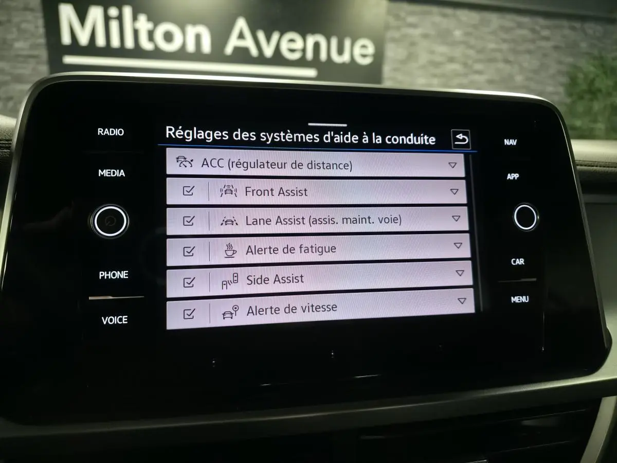 Écran tactile du tableau de bord du Volkswagen T-Roc gris 2024 affichant les réglages des aides à la conduite.