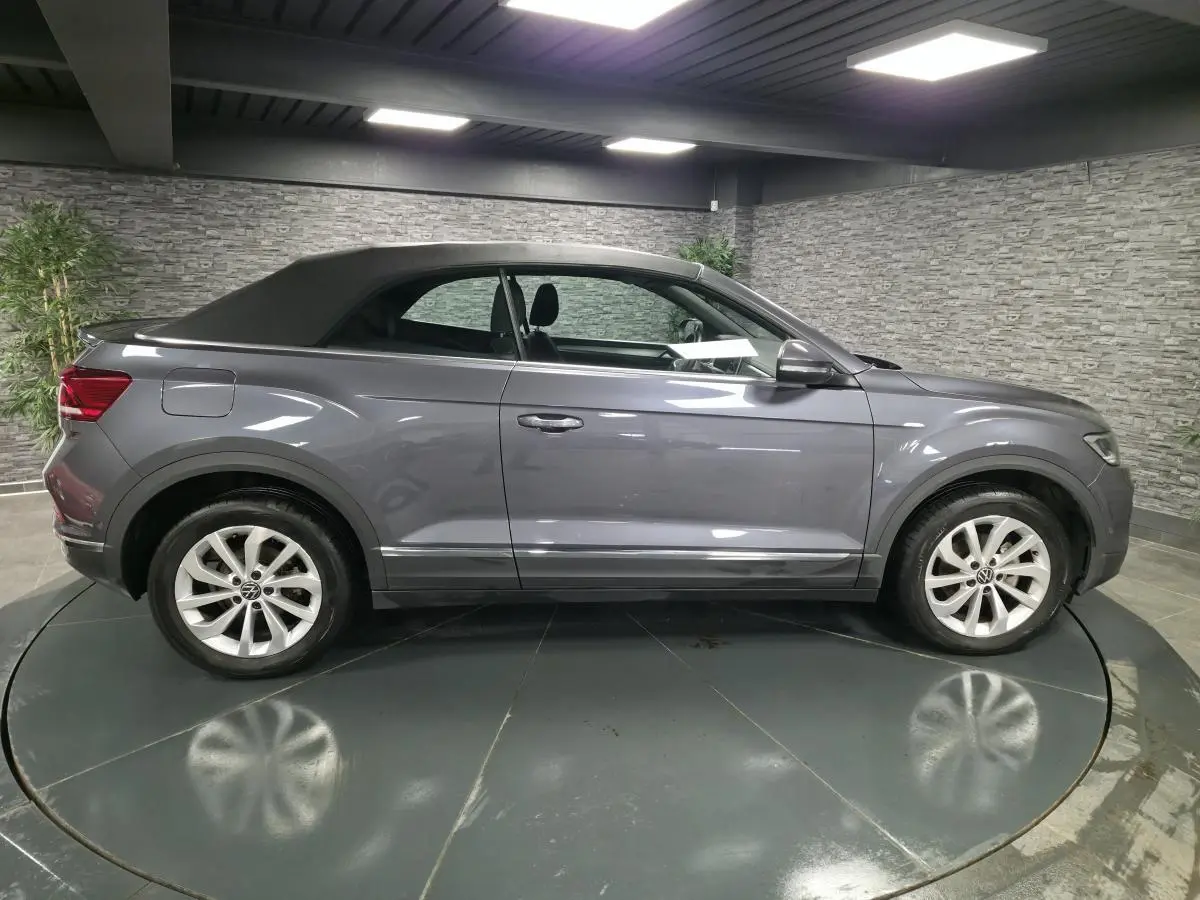 Volkswagen T-Roc cabriolet gris métallisé vue de profil côté gauche, capote noire fermée, jantes alliage 17 pouces.