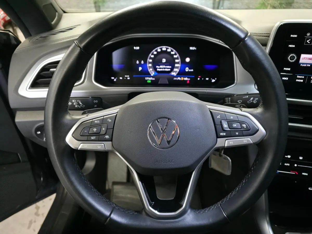 Vue rapprochée du volant en cuir noir et du tableau de bord numérique du Volkswagen T-Roc 2024 cabriolet gris.