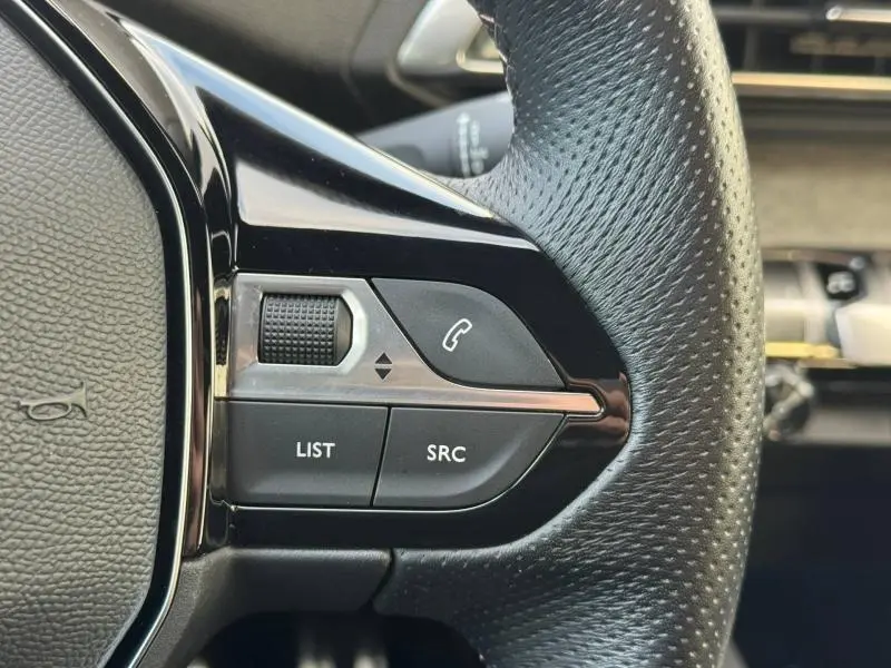 Gros plan sur les commandes gauche du volant noir du Peugeot 3008 1.2 PureTech 130ch GT 2024, boutons LIST, SRC et téléphone.
