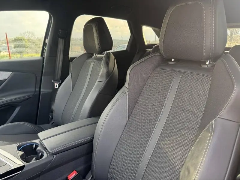 Vue intérieure du Peugeot 3008 2024 noir, montrant les sièges avant en tissu et cuir avec surpiqûres contrastantes.