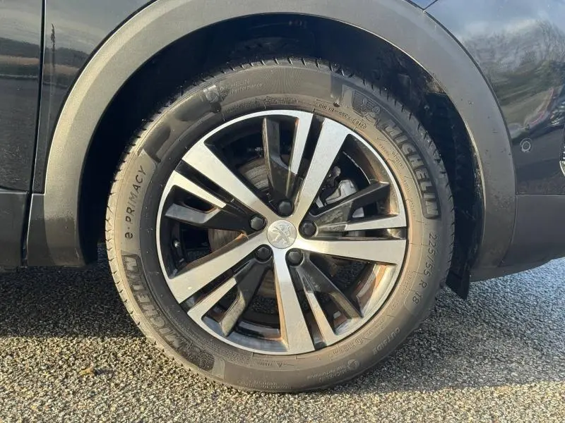 Gros plan sur la roue avant gauche du Peugeot 3008 noir 2024, jante alliage à cinq doubles branches et pneu Michelin.