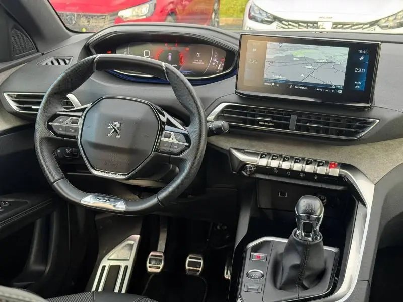 Intérieur du Peugeot 3008 2024 noir, vue centrée sur le volant, tableau de bord numérique et levier de vitesses manuel.