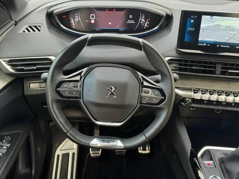 Vue intérieure centrée sur le volant noir du Peugeot 3008 2024 GT avec tableau de bord numérique et écran tactile.
