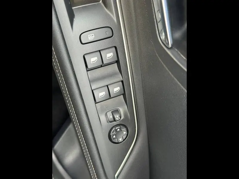 Détail des commandes des vitres et rétroviseurs sur la porte côté conducteur d’un Peugeot 3008 noir 2024.