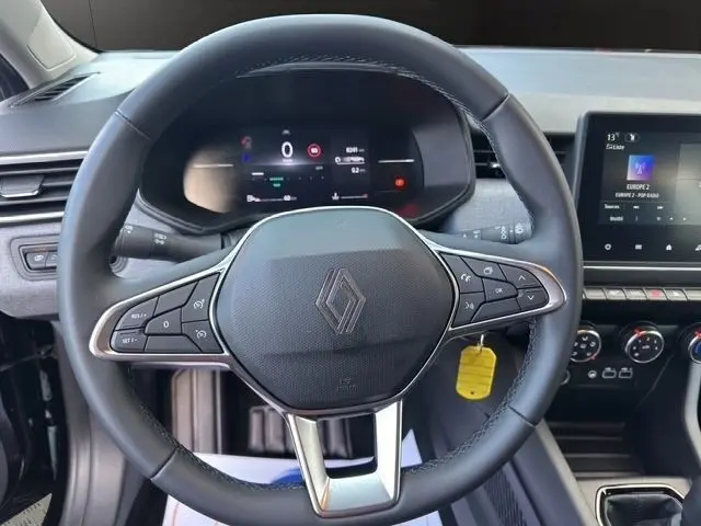 Vue rapprochée du volant cuir synthétique multifonctions noir de la Renault Clio 2025 avec tableau de bord numérique et écran tactile central.