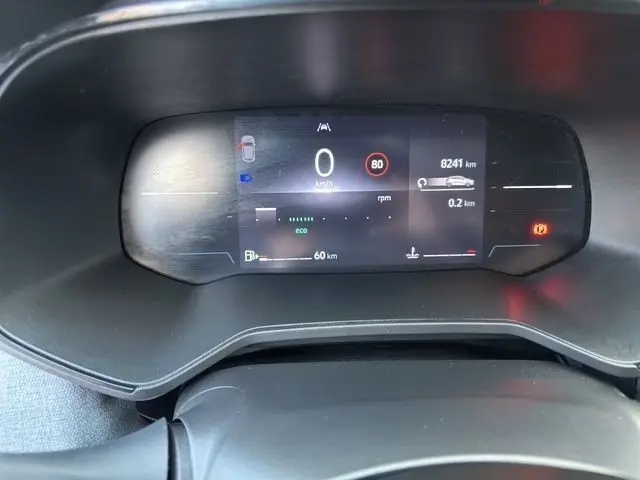 Vue rapprochée du combiné d'instruments numérique de la Renault Clio noir, affichant la vitesse à 0 km/h et diverses alertes.