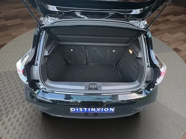 Vue arrière ouverte sur le coffre spacieux d'une Renault Clio noire 2025, intérieur noir et éclairage latéral actif.