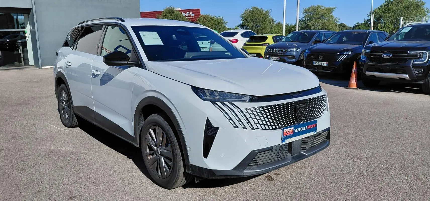 Peugeot 5008 Hybrid blanc vue 3/4 avant droit, calandre moderne avec logo lion et jantes alliage.