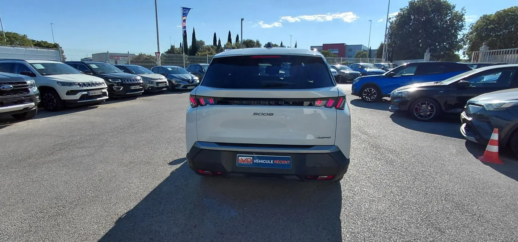 Vue arrière d'un Peugeot 5008 blanc 2025 Hybrid 145 ch avec feux arrière LED distinctifs, stationné en extérieur.