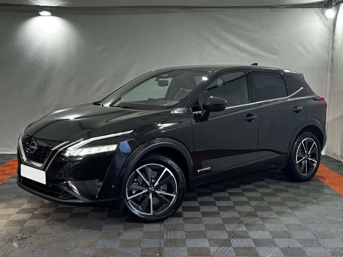 Nissan Qashqai e-Power noir en 3/4 avant droit, avec jantes alliage et phares LED allumés dans un studio.