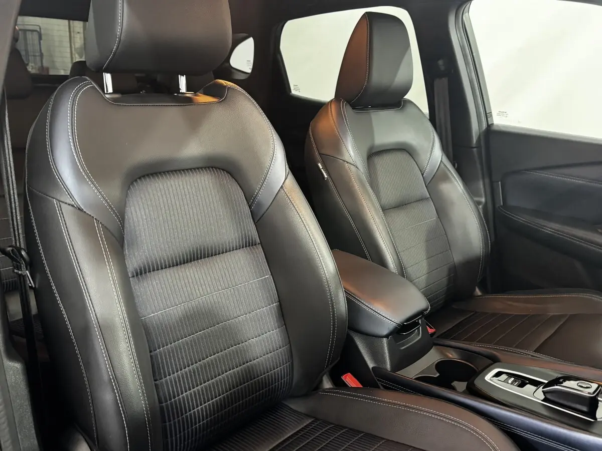 Intérieur du Nissan Qashqai e-Power 2023, vue rapprochée des sièges avant en cuir noir avec surpiqûres blanches.