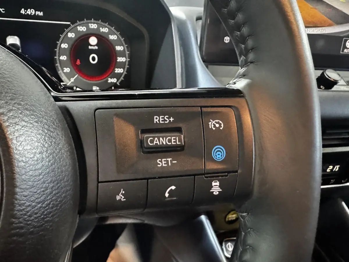 Gros plan sur le volant noir du Nissan Qashqai e-Power 190 Tekna 2023, avec commandes de régulateur de vitesse et affichage numérique en arrière-plan.