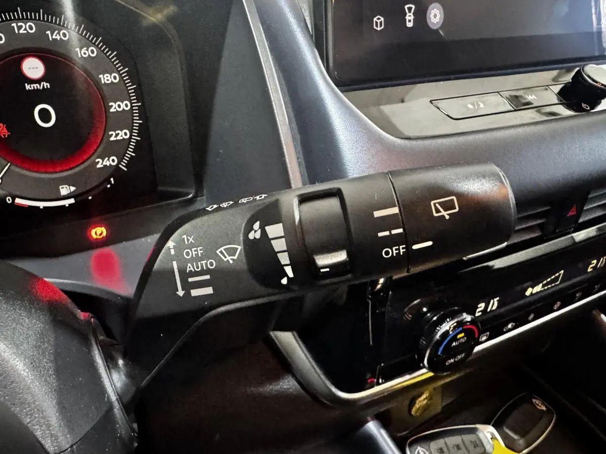 Gros plan sur la commande d’essuie-glace et le tableau de bord numérique du Nissan Qashqai e-Power noir 2023.